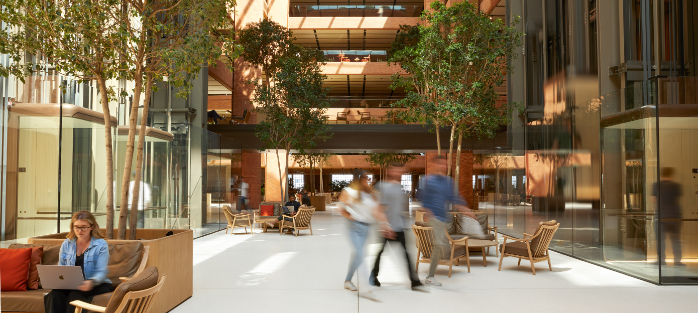 L’étage inférieur de l’atrium Battersea lumineux, avec plusieurs membres de l’équipe Apple qui se rencontrent, se promènent et travaillent assis.