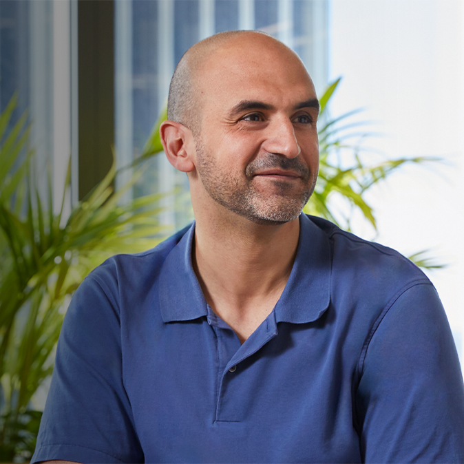 Ahmed assis à l’intérieur, souriant et regardant hors champ vers sa gauche.