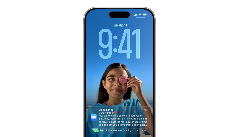 iPhonen lukittu näyttö, jolla näkyy kuva, kellonaika Liquid Glass ‑ulkoasulla ja näytön alareunassa kaksi ilmoitusta