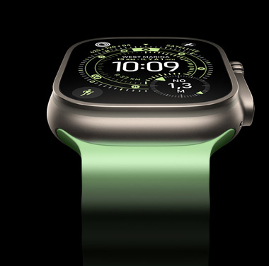 Gros plan d’une Apple Watch Ultra 3 en titane naturel sur fond noir. L’écran affiche l’heure et d’autres données dynamiques.