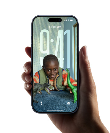 一隻手拿著 iPhone 裝置，展示全新 Liquid Glass 設計，讓時間顯示隨鎖定畫面上的影像動態調整