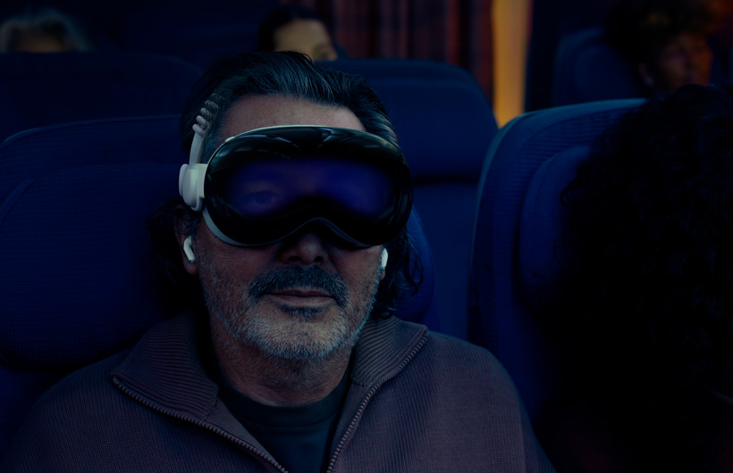 شخص يجلس في طائرة ويضع على وجهه Apple Vision Pro تم تجميعه مع الحزام الثنائي المغزول