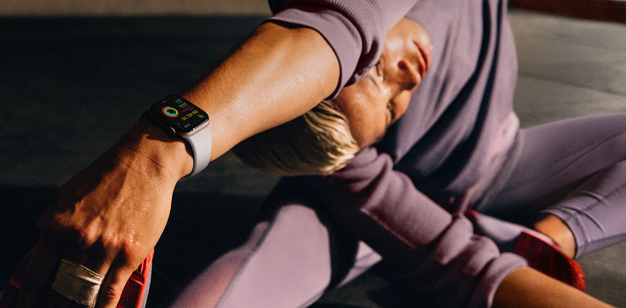 Eine Frau, die beim Dehnen eine Apple Watch trägt.